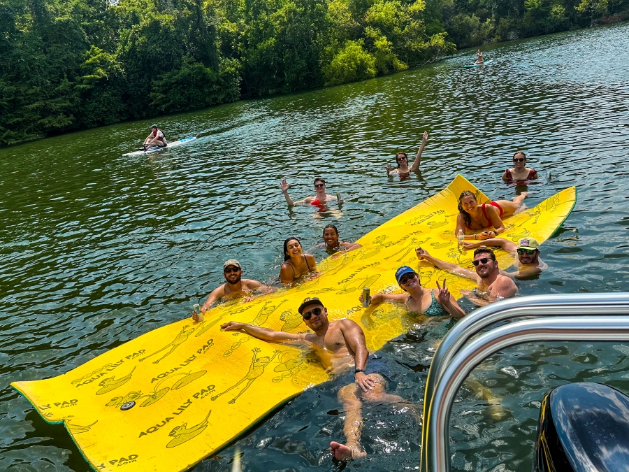 Group of adults celebrating a birthday on a Wake Riderz boat, with Austin skyline in the background.