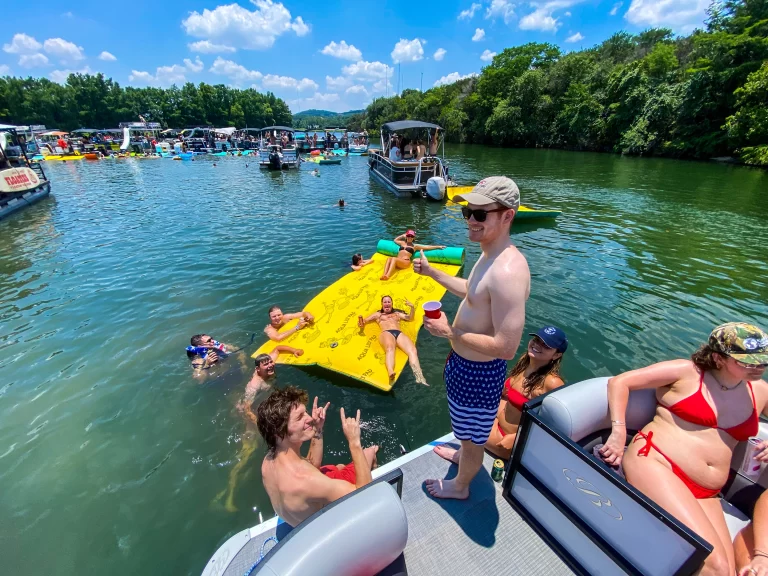Guests swimming and relaxing on a floating water mat beside a Wake Riderz boat on Lake Austin