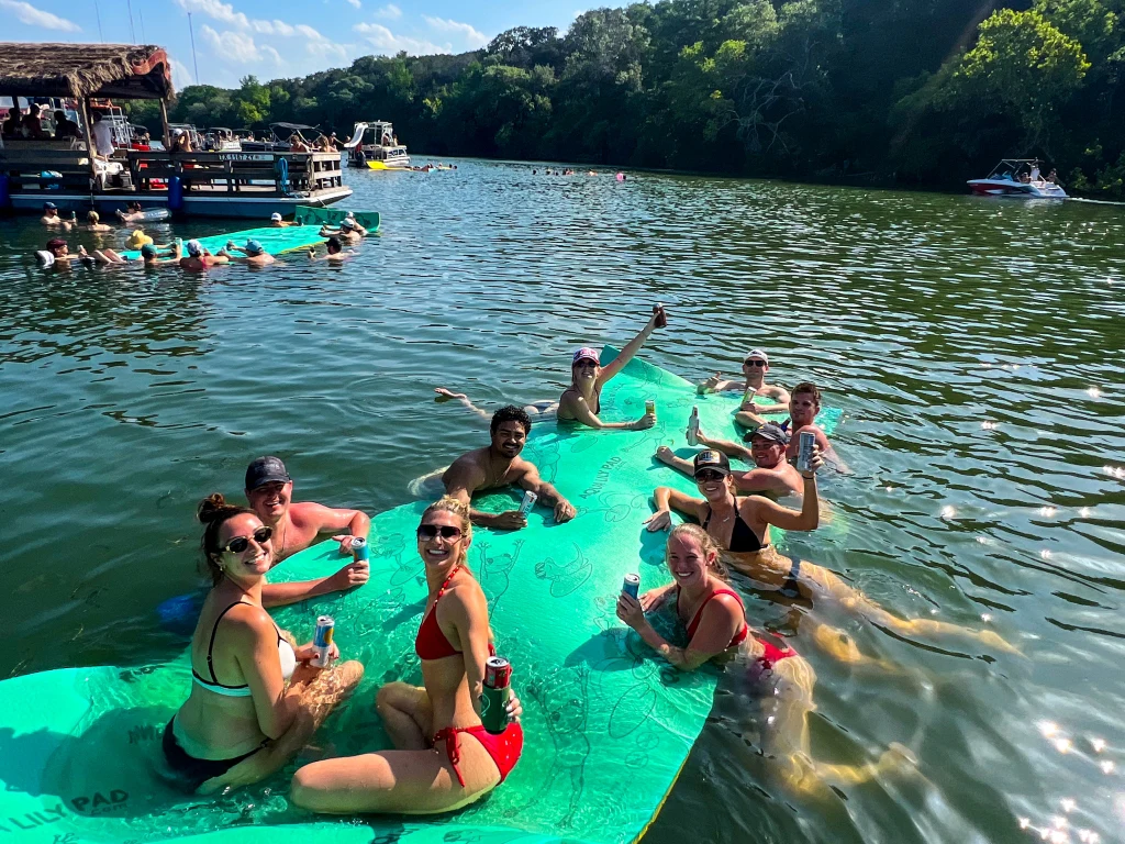 Group relaxing on floating water mats during a private boat party on Lake Austin