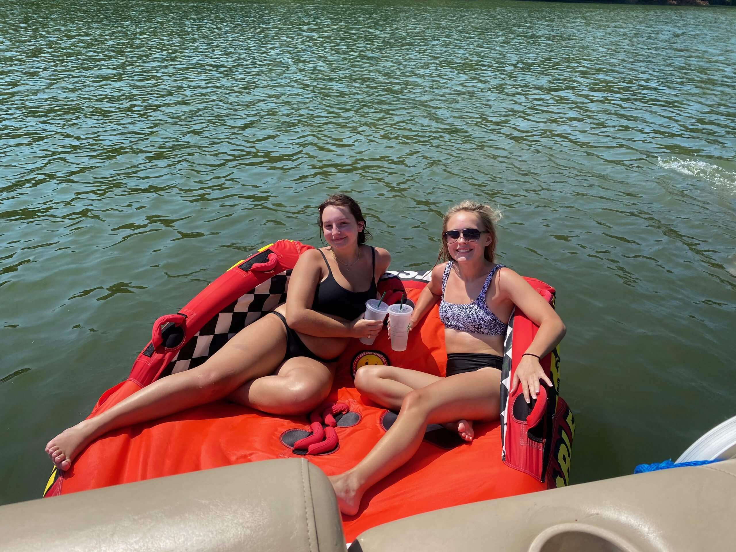 Two girls water tubing on their boat rental Lake Austin experience.