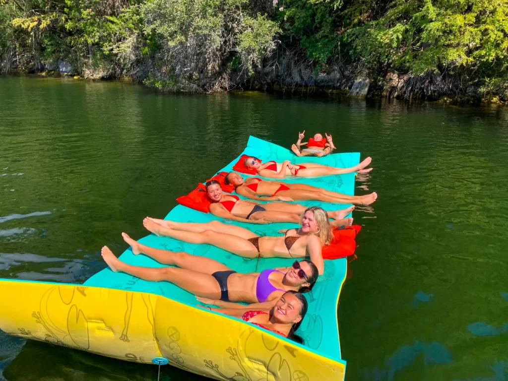 Coworkers relaxing on a floating mat during a corporate boat tour on Lake Austin