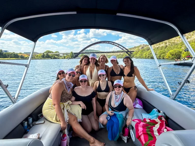 Bachelorette group wearing matching hats during a fun captained boat tour on Lake Austin with the Pennybacker Bridge in view