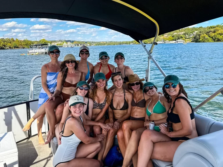 Group of women posing together on a captained pontoon boat during a sunny Lake Austin outing