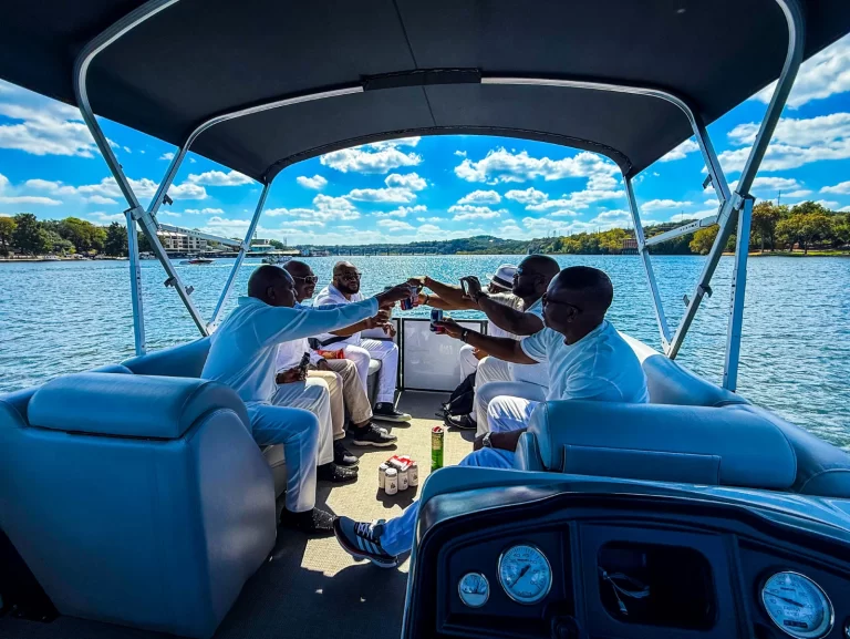 Friends dressed in white raising a toast together on a captained boat cruise on Lake Austin