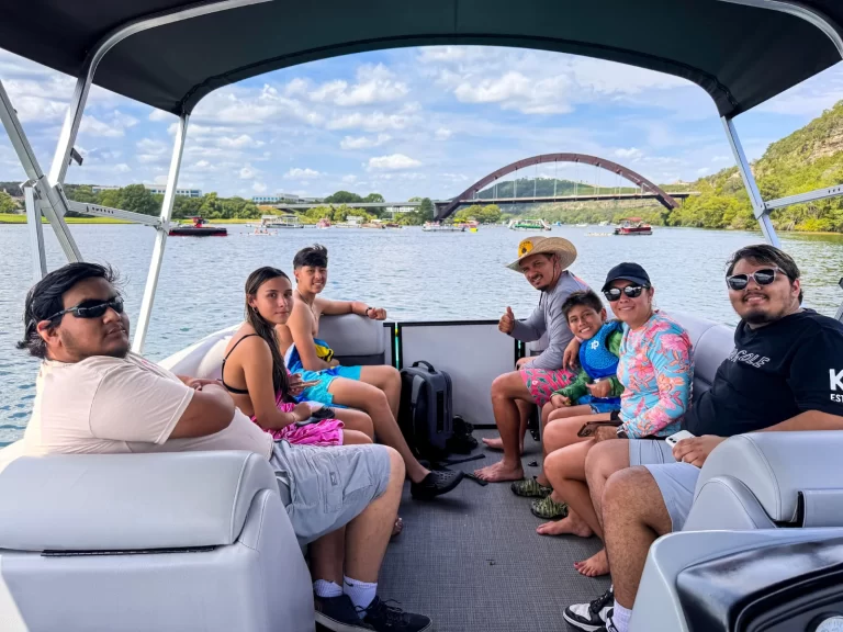 Family enjoying a Lake Austin captained boat tour with a view of the Pennybacker Bridge
