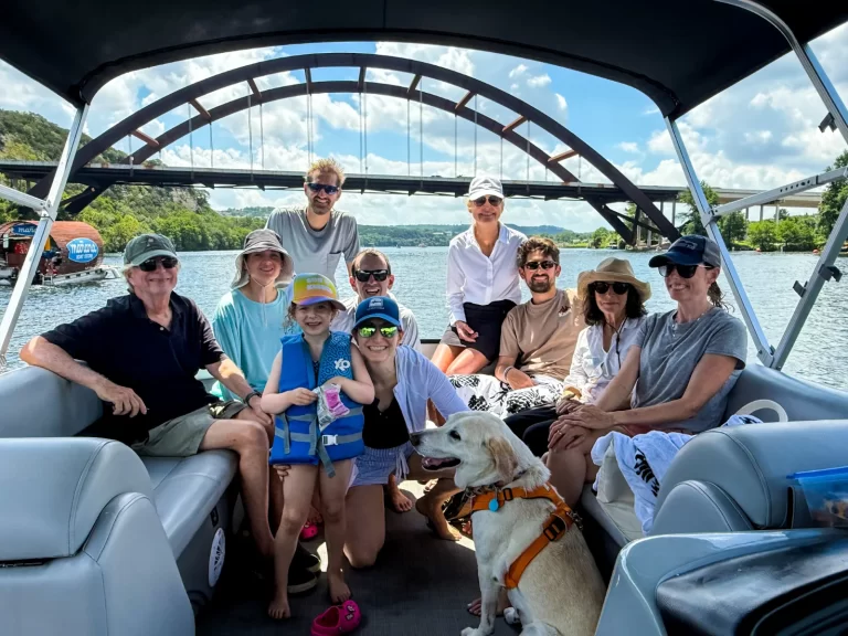 Family and dog enjoying a captained pontoon boat tour on Lake Austin with the Pennybacker Bridge behind them