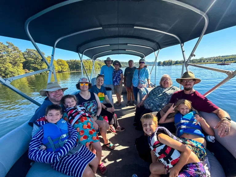 Large family enjoying a sunny Lake Austin pontoon boat tour surrounded by early fall colors