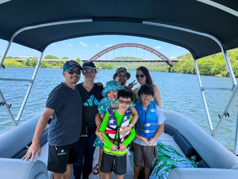 Family enjoying a captained pontoon ride on Lake Austin with the iconic Pennybacker Bridge behind them