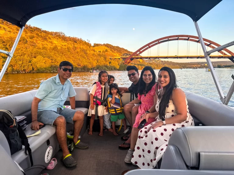 Family enjoying a golden sunset boat tour on Lake Austin with the Pennybacker Bridge behind them