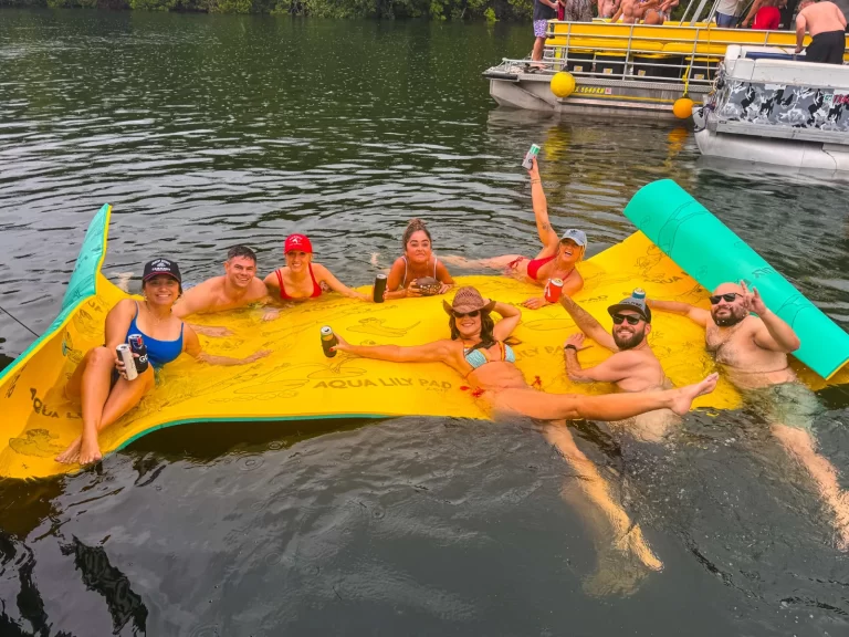 Group relaxing on a floating Aqua Lily Pad during a fun Lake Austin party boat rental