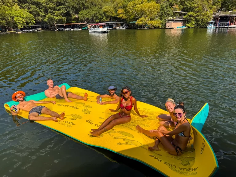 Friends relaxing on a floating pad in a quiet Lake Austin cove during a captained boat rental