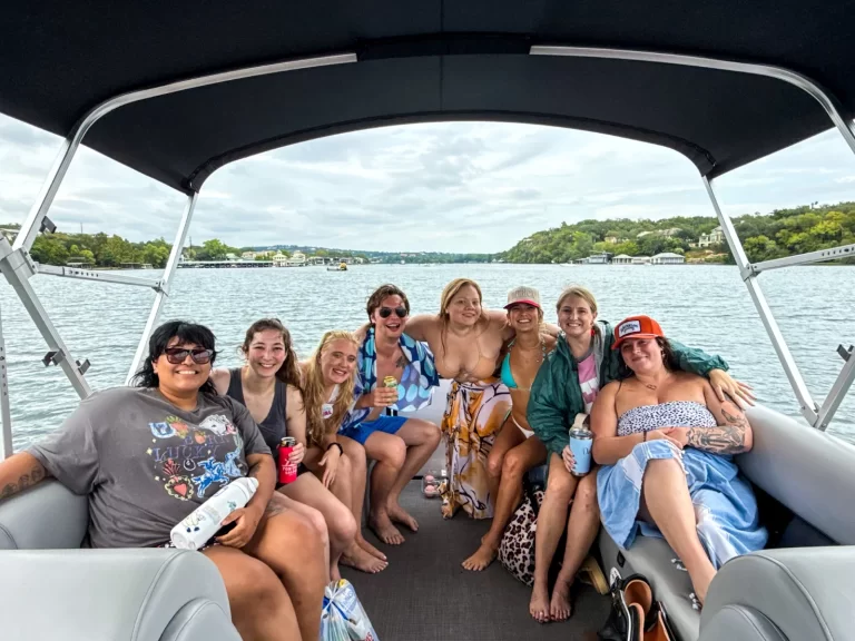 Group of friends smiling and relaxing on a pontoon boat during a Lake Austin captained boat rental