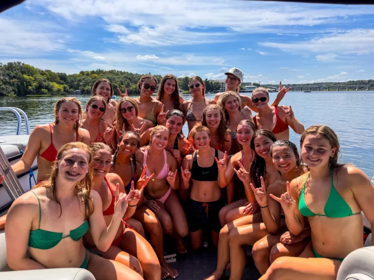 Large group of girls making Texas hand signs during a fun Lake Austin pontoon boat tour