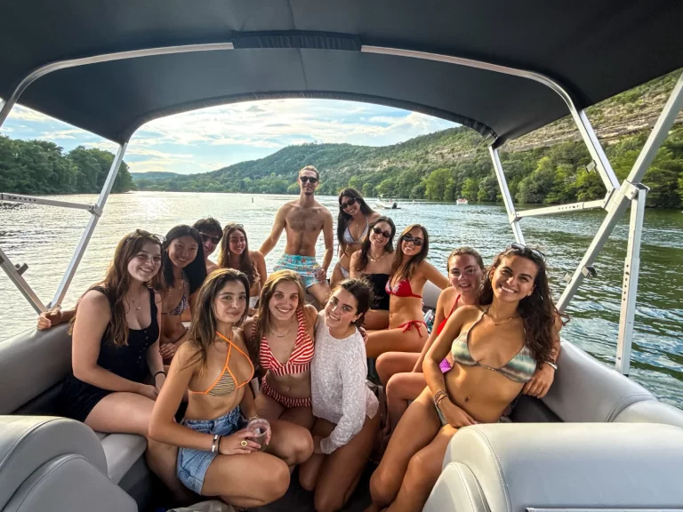 Large group enjoying a summer captained boat cruise on Lake Austin with scenic shoreline views