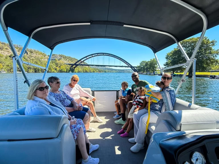 Family enjoying a calm and scenic captained pontoon boat tour on Lake Austin with the Pennybacker Bridge nearby